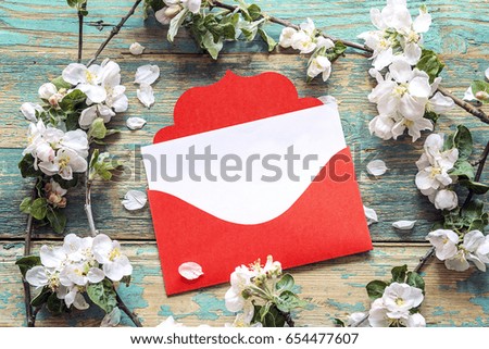 Red envelope with apple blossom on old wooden background. Space for text. Spring flowering branch.