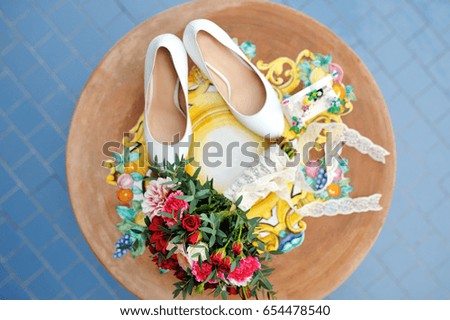 Bridal bouquet and white shoes on a wooden table in wedding day