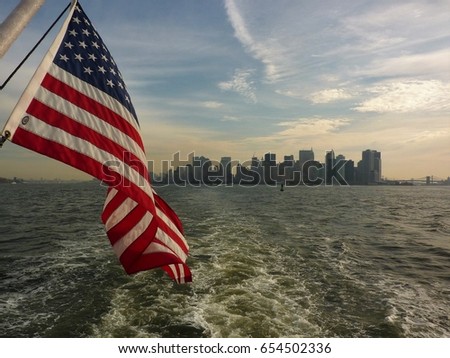 American flag curling in the wind in front of a hazy New York Skyline. Picture taken on the Hudson River in the early morning. 