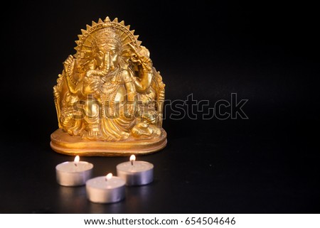 Ganesha lord of arts, Lord Ganesh sculpture,Hindu golden statue of ganpati with candle lights.