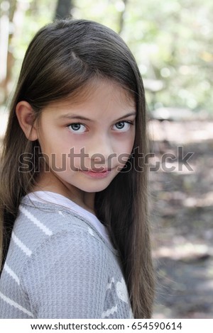 Young pre-teen kid with long hair looking directly into the camera.