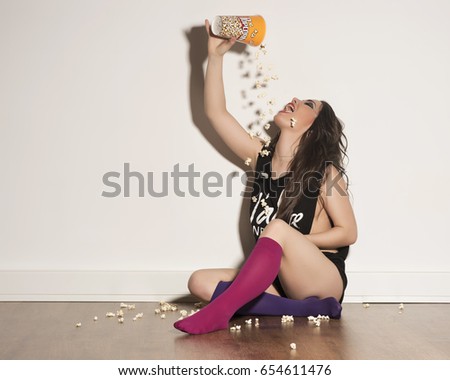 beauty girl in underwear playing with popcorn throwing to her mouth