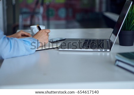 Woman working behind laptop at office                               