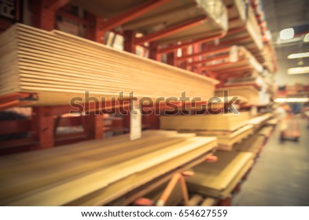 Blurred wooden bars from floor to ceiling at lumber yard of hardware store in America. Rack of pre-cut panel, mill wood timber, red oak, poplar, cedar, whitewood board, siding, plywood on flatbed cart Royalty-Free Stock Photo #654627559