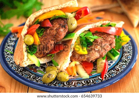 Pita bread with fried pork chop and vegetable, olive, spring picnic. Wooden background. Top view. Close-up