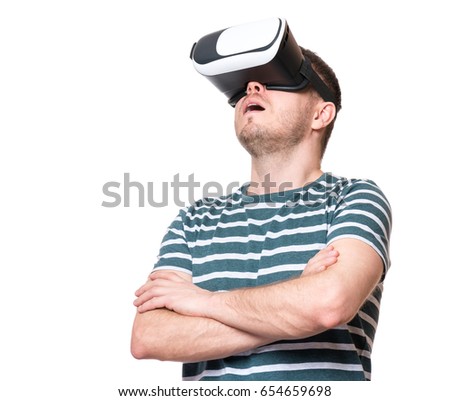 Amazed man wearing virtual reality goggles watching movies or playing video games, isolated on white background. Surprised male in VR glasses. People experiencing 3D technology.