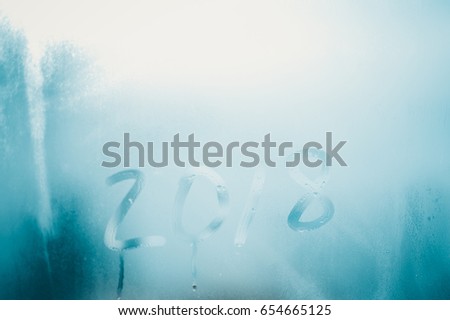 Closeup image of the 2018 inscription sign on condensated glass blurred translucent effect window. Creative monochrome foggy copyspace