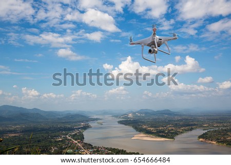 UAV drone copter flying with digital camera.Drone with high resolution digital camera. Flying camera take a photo and video.The drone with professional camera takes pictures of the river and mountains