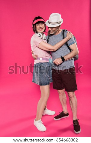 stylish cheerful man and woman hugging each other isolated on pink