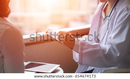 Professional medical doctor in white uniform gown coat interview counseling female patient: Physician writing on patient chart while consultation: Hospital/ clinic healthcare professionalism concept Royalty-Free Stock Photo #654674173