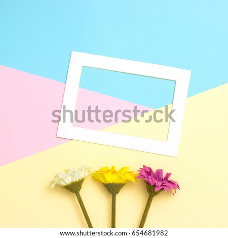 Empty frame and flowers flat lay on pastel background with copy space. Soft effect filter. Minimal concept.