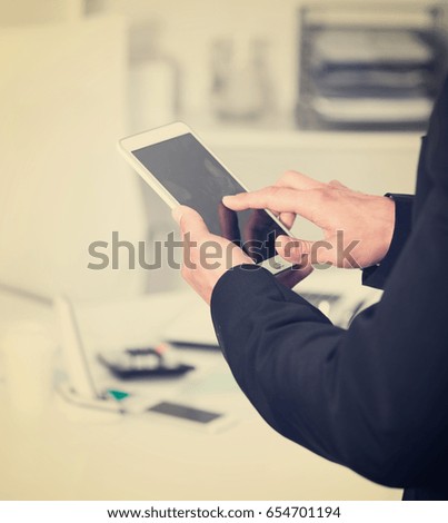 Businessman holding and using smartphone at workplace in office