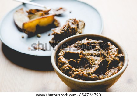 Food from side. Healthy rustic snack on ceramic plate and bowl. Rustic aubergine and pepper dip, homemade spinach bread on wooden table background.