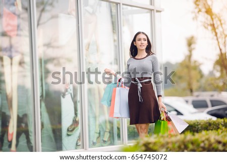 happiness, consumerism, sale and people concept - smiling young Asia woman with shopping bags at outdoor shopping mall