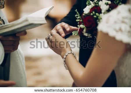bride and groom exchanging wedding rings, putting on fingers during wedding ceremony in church. wedding couple