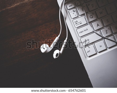 This is white headphone and white laptop on wooden table,  soft tone