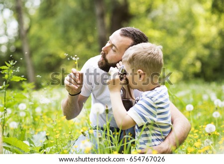 Young father with little boy with camera in summer park.