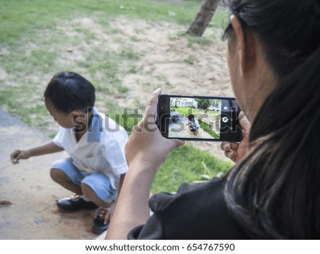 a mom taking picture of her child while playing, using smartphone. selective focus at smartphone