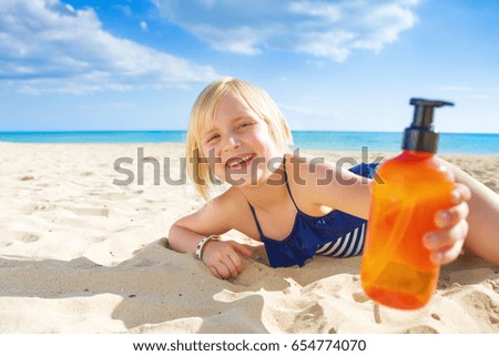 Sun kissed beauty. smiling blond child in swimsuit on the seashore showing sun screen