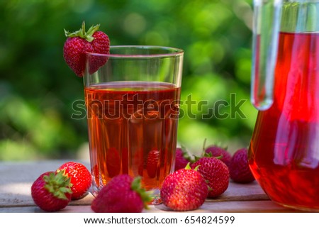 glass with strawberry juice and berries isolated on blur background