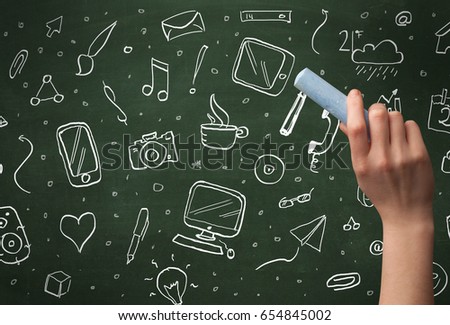 A person drawing media and communication icons on school blackboard with chalk