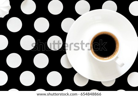 Top view, hot coffee in a white cup. Black and white peas background of a table surface. Home stylish decor.