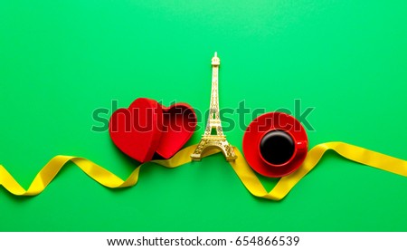 Heart shape box and Eiffel tower with cup of coffee on green background