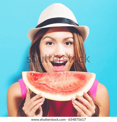 Happy young woman holding watermelon on a blue background