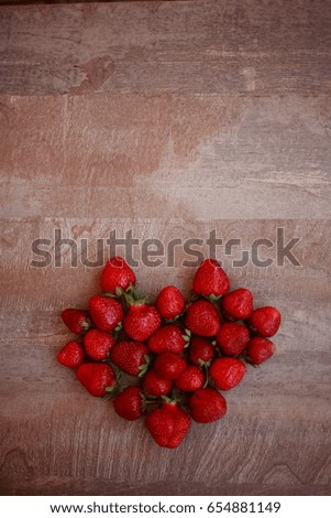 Strawberries in a form of a heart on a wooden table.