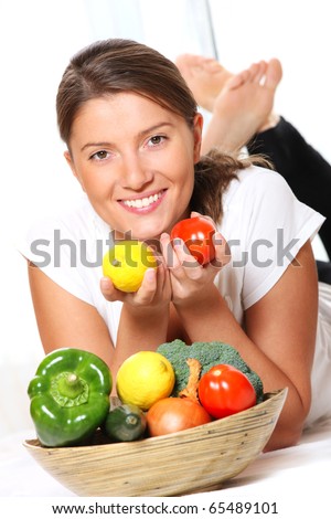 A picture of a young pretty woman with a basket full of vegetables over white background