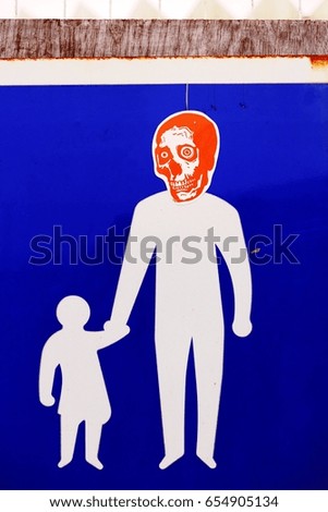 Road sign with an adult and a child. Someone put a skull sticker on the adult's head