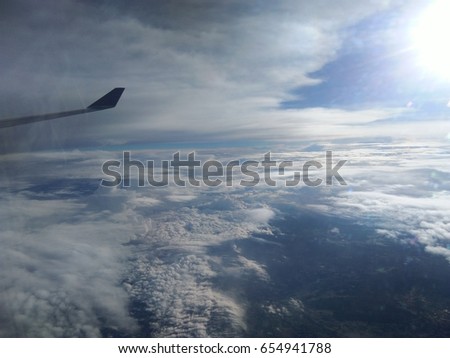 Wing of Airplane on the blue sky, near pure white fluffy clouds like pandas.