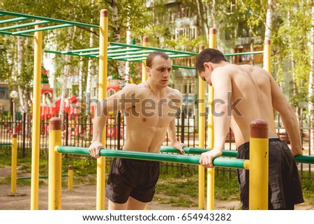 Fitness men at the bar. Exercising outdoors in the Park. Street workout.