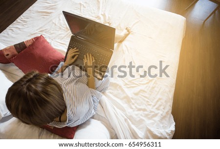 Top view,Woman using a laptop on bed.