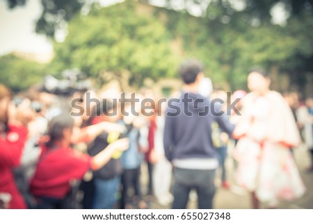 Blurred male reporter holding microphone with cameraman operator recording/videotaping an interview with a beautiful celebrity at a public event in Hanoi. Reporting and public speaking. Vintage tone.