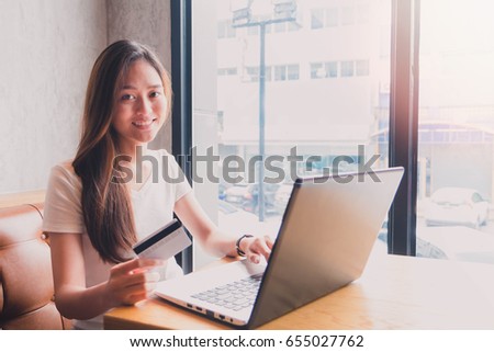 Young beautiful asian woman using laptop and shopping with credit card in coffee shop background