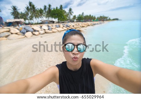Asian girl in sunglasses taking selfie on the tropical beach