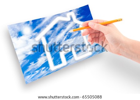Female hand with a pencil draws a house of clouds against the sky.