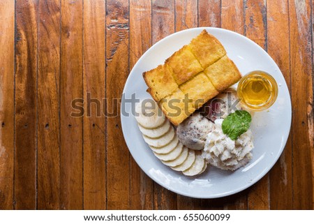 honey toast with ice cream, strawberry and banana on wood table