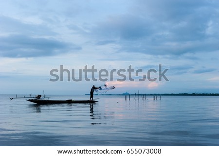 silhouette of fisherman on boat with beautiful sunset sky in  in wetlands Thale Noi, South of THAILAND.