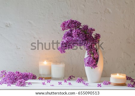 flowers in vase with candles on background white wall