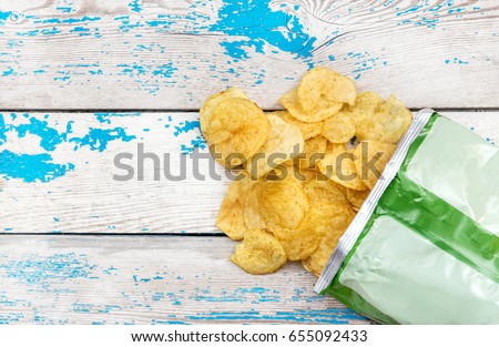 Potato chips scattered with packaging on the table. Top view. Royalty-Free Stock Photo #655092433