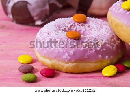 Assortment of colorful donuts with candies on pink wooden background