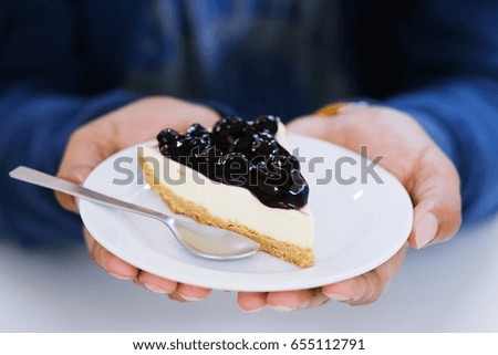person holding Cake blueberry in a serving plate the taste yummy. 