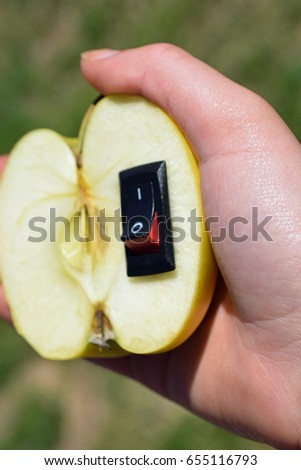 Woman holding a fresh apple. Power switch inserted on fruit. Healthy food and healthier lifestyle concept. Vertical image