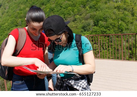 Two young Tourists With Backpacks travel, looking a paper map. Active hikers
