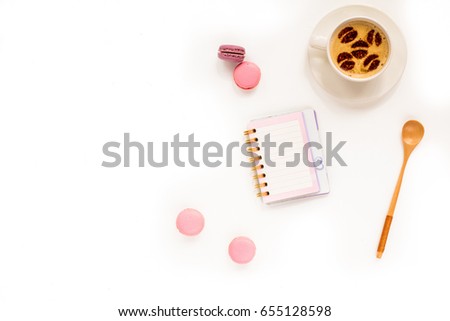 Feminine desk workspace. Cake macaroons, cup of coffee, notebook empty blank and flowers on white background. Flat lay, top view