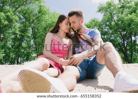 Young couple hugging and smiling at each other on the river bank. Walking along the sandy beach.