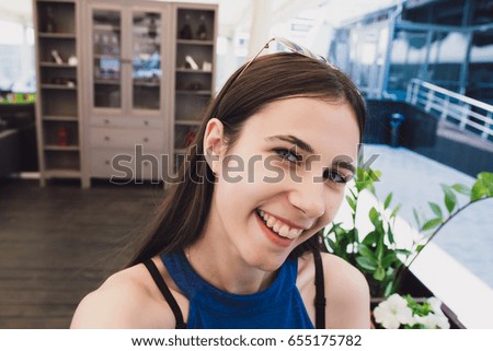 A very pretty girl doing selfie at a cafe.