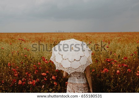 Woman posing in Poppies field with umbrella. Artistic interpretation